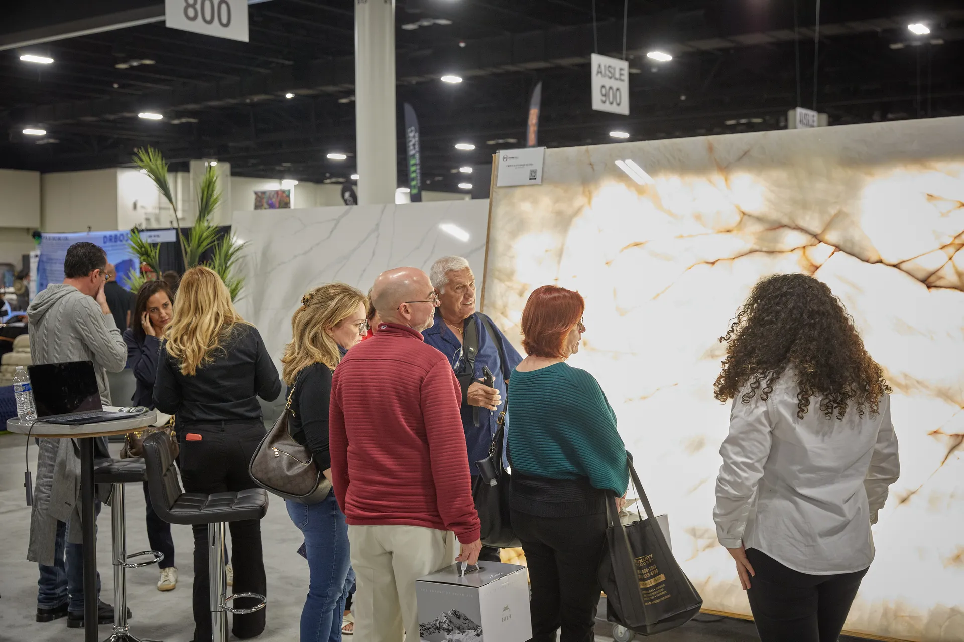 Attendees walking past a Home Design Stage banner and large stone slab display at the home show