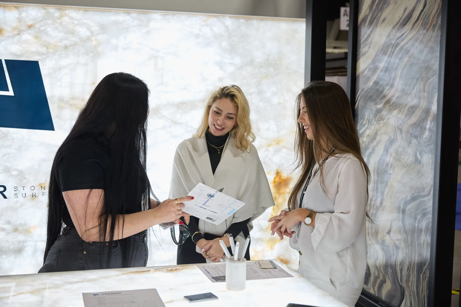 Attendee photographs a luxury furniture display at a home show with her smartphone