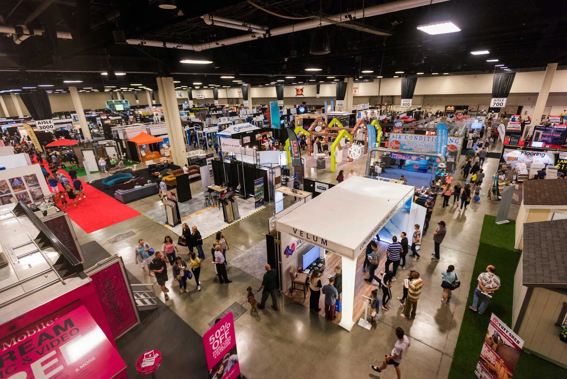 Busy home show convention floor with hundreds of attendees among exhibitor booths